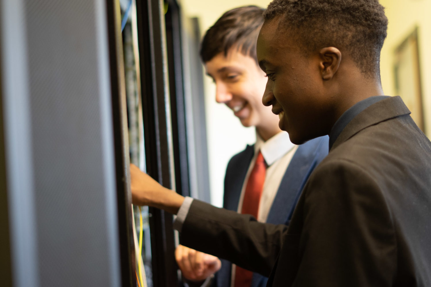 Two Leigh UTC students are shown smiling whilst working on computer hardware.