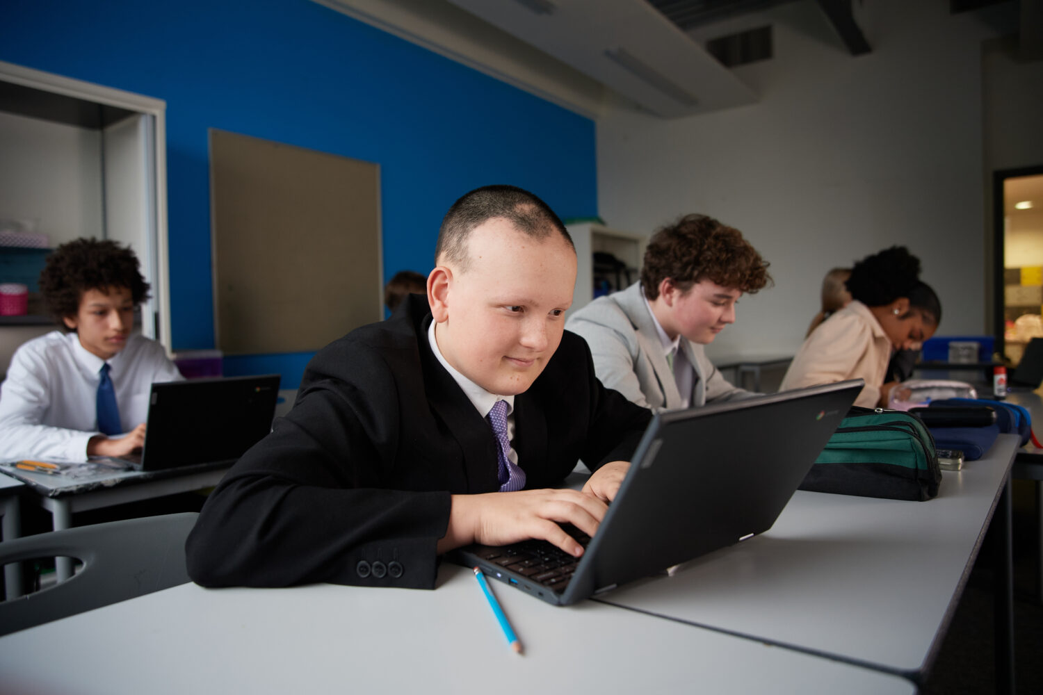A small group of Post-16 students are shown sitting quietly in a classroom, focusing on their work individually.