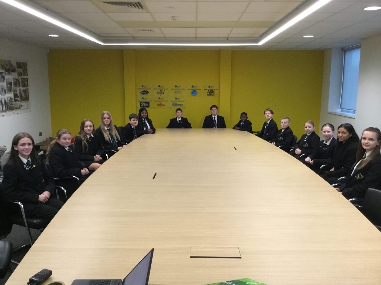 A group of students sat around a large table, smiling for a photo
