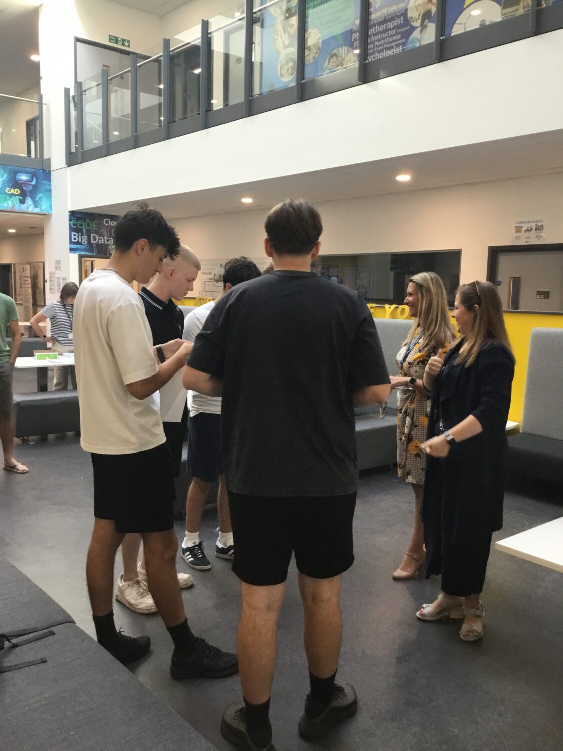 A group of Post-16 students are pictured smiling together with staff, whilst looking at their A-Level results.
